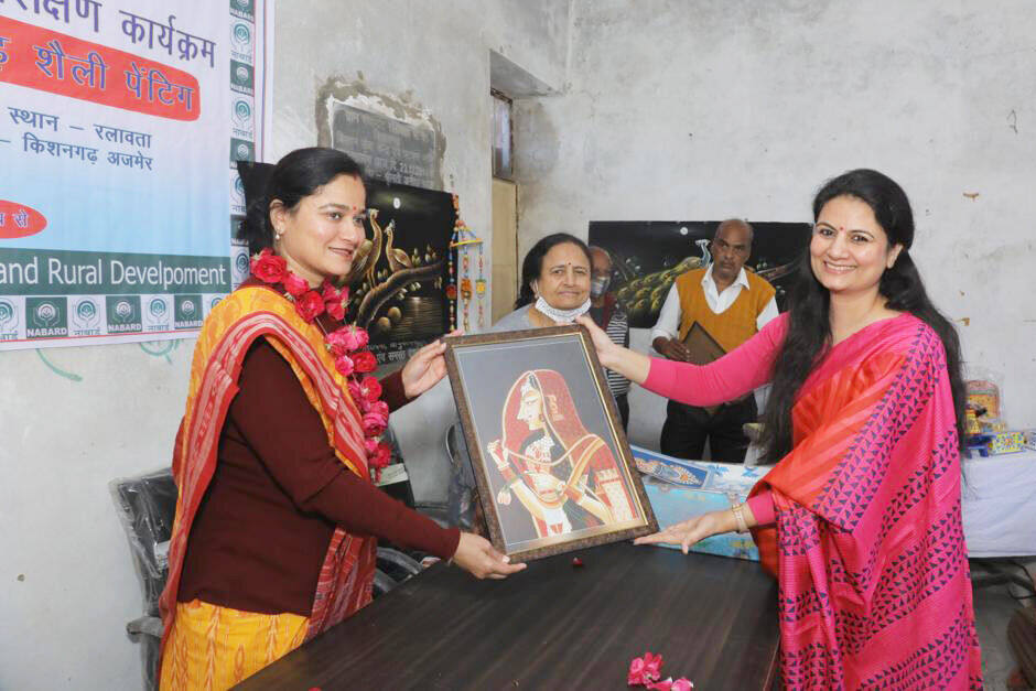 Trainees presenting a finished Bani Thani painting at a NABARD-banner event, Ralawata