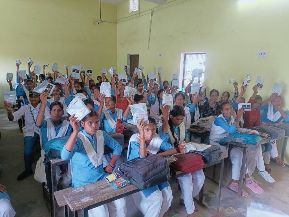 Schoolgirls holding up sanitary pad packets, Mughalsarai, Chandauli district