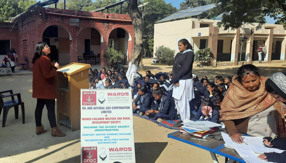 Speaker addressing seated students from the podium, Village Pahari