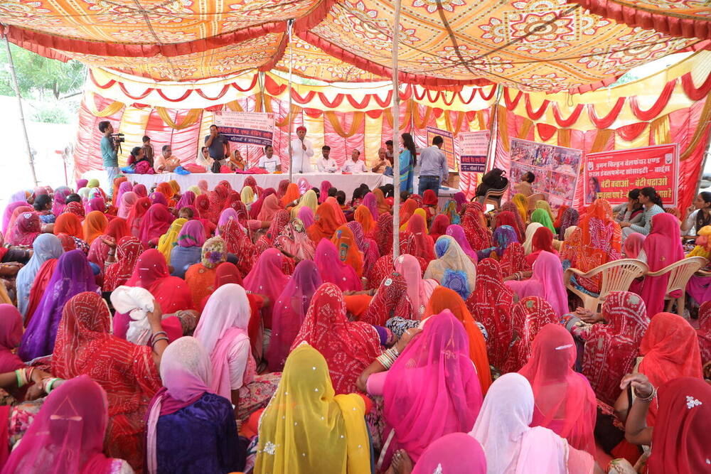 Hundreds of village women gathered under a decorated tent, Ralawata
